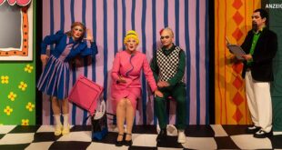 Szenenfoto: Frau Marthe sitzt neben Richter Adam. Sie hat ihre linke Hand auf seinem rechten Knie. Links steht Eve, sie lauscht. Schreiber Licht protokolliert.